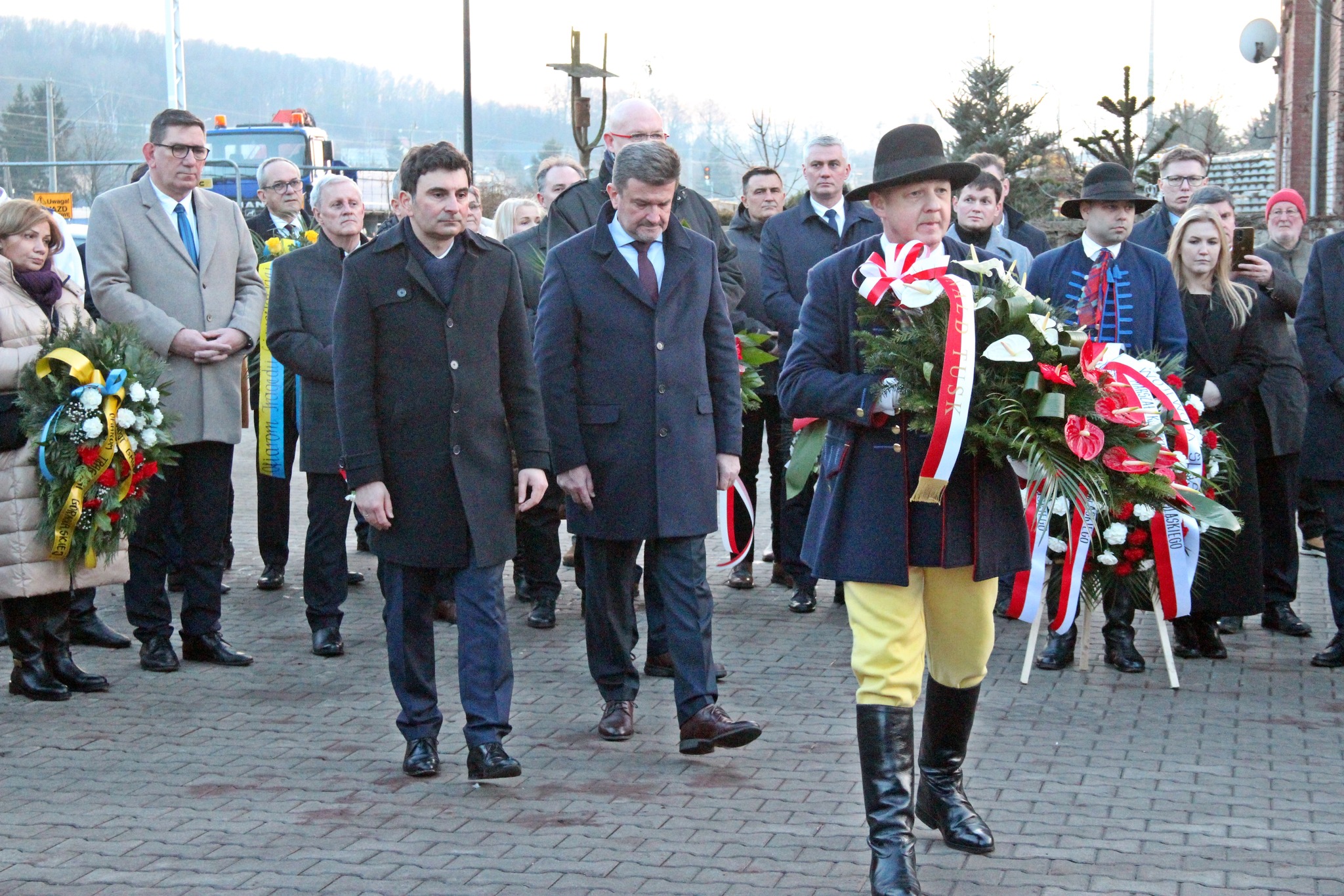 Uczestnicy wydarzenia składają wieniec przed tablicą pamiątkową