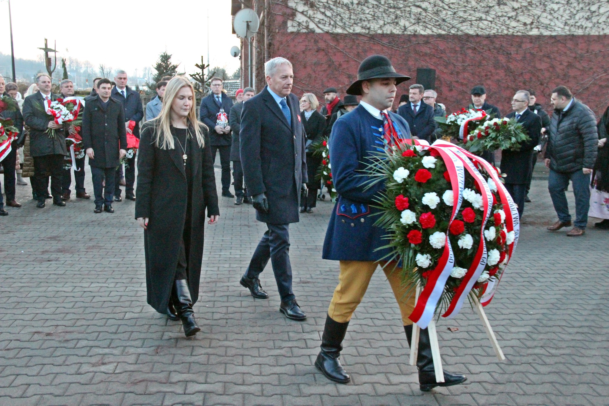 Delegacja składa wieniec przed tablicą pamiątkową